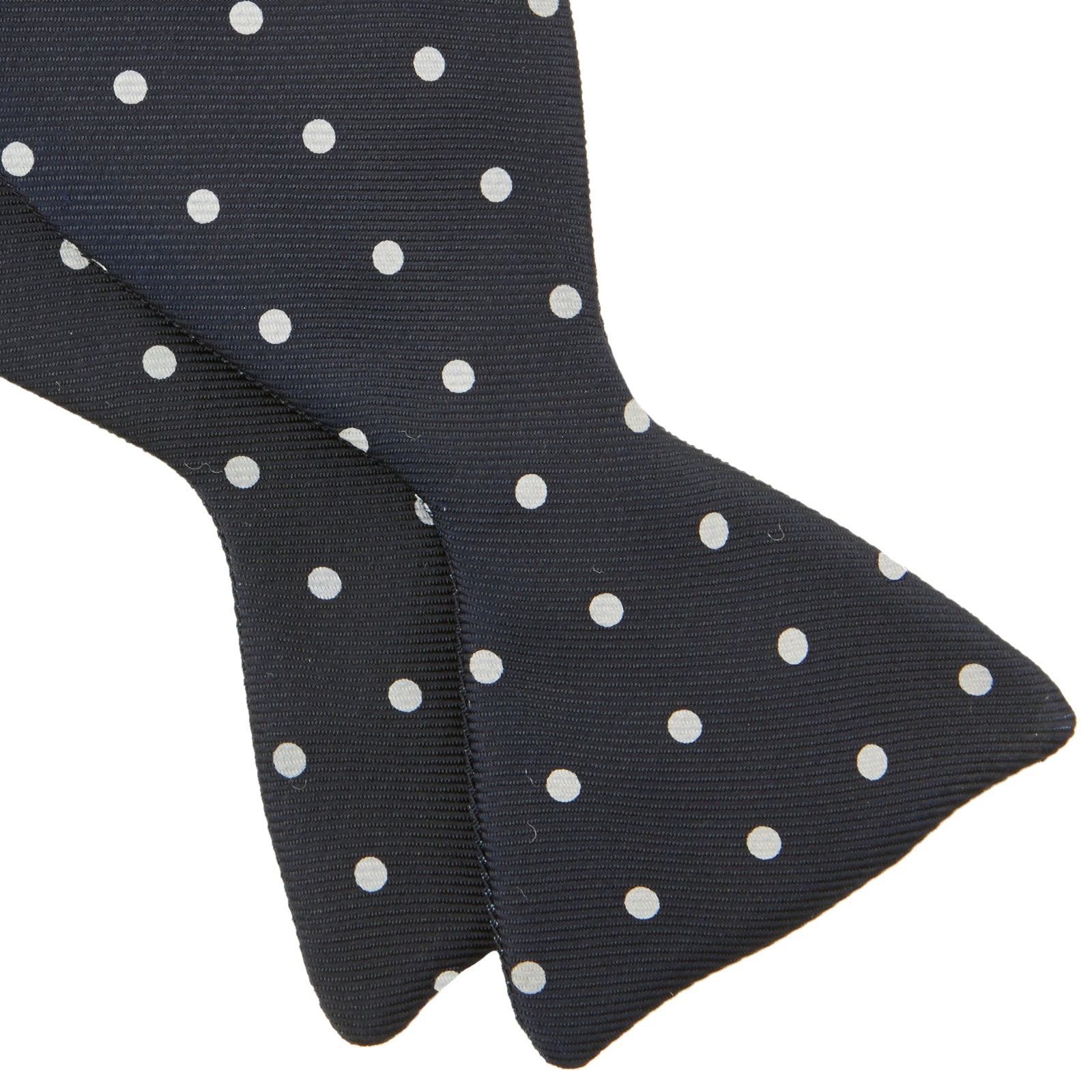 View 4 of product The Winston Navy and White Spot Silk Bow Tie by Turnbull & Asser features classic white polka dots on navy silk, reminiscent of Winston Churchill's style, and is shown against a plain white background.