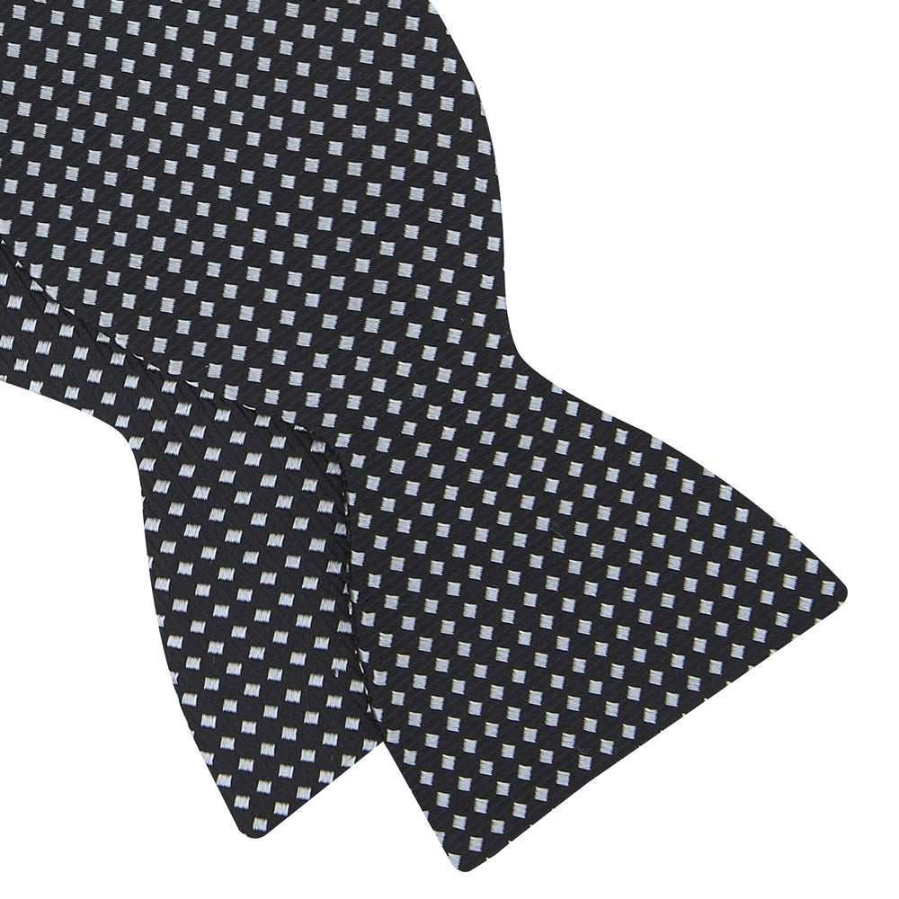 The Turnbull & Asser Diamond Black and White Silk Bow Tie features a black woven silk design with a tessellated diamond pattern of small white shapes, shown against a plain white background.