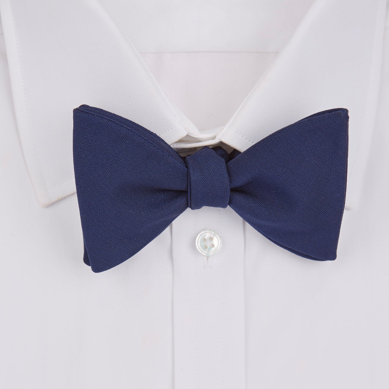 View 2 of product The Turnbull & Asser Navy Barathea Bow Tie features a classic butterfly shape in deep blue silk, ideal for formal occasions, shown against a white background.