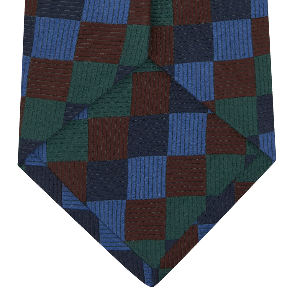 The Turnbull & Asser Navy and Blue Checkerboard Jacquard Wool Tie showcases a stylish checkered pattern, ideal for adding refined autumn tones to your ensemble.