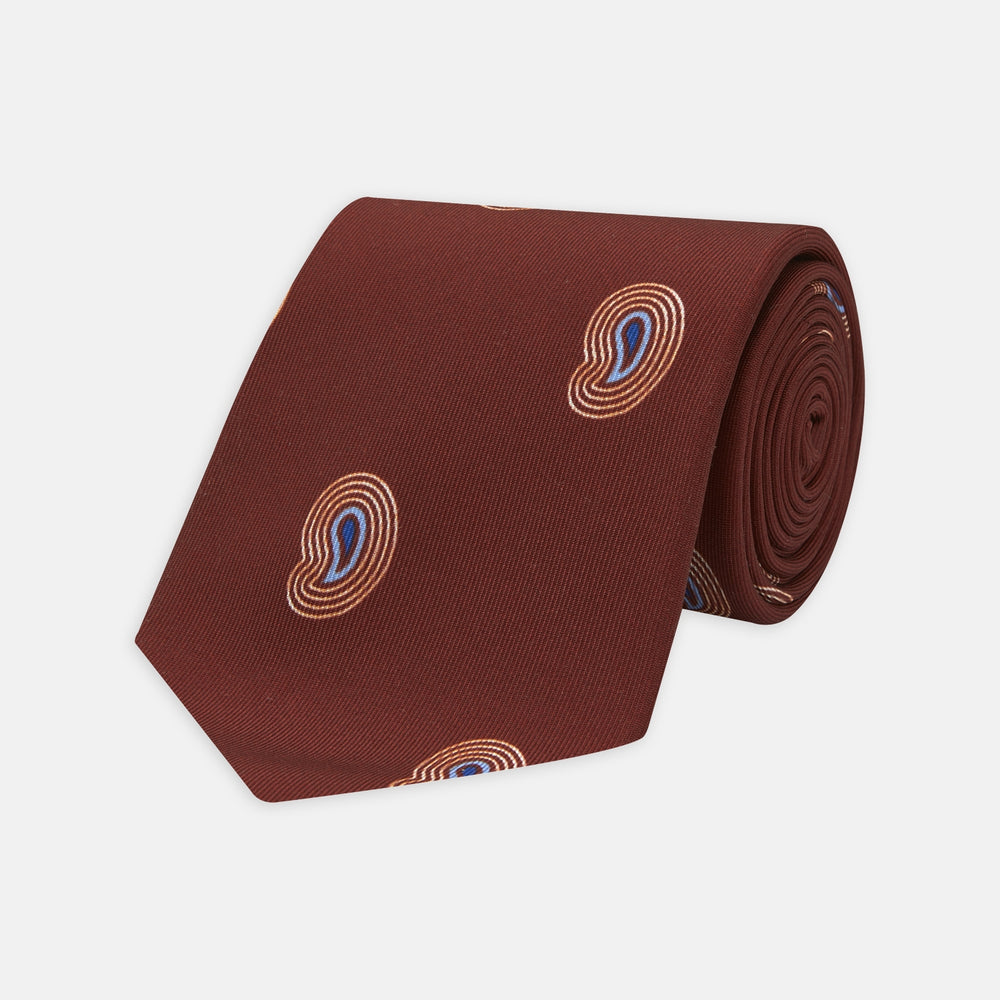 The Turnbull & Asser Red Pulse Paisley Silk Tie features a rolled red silk design with a repeating pattern of tan, blue, and white abstract pulse motifs.