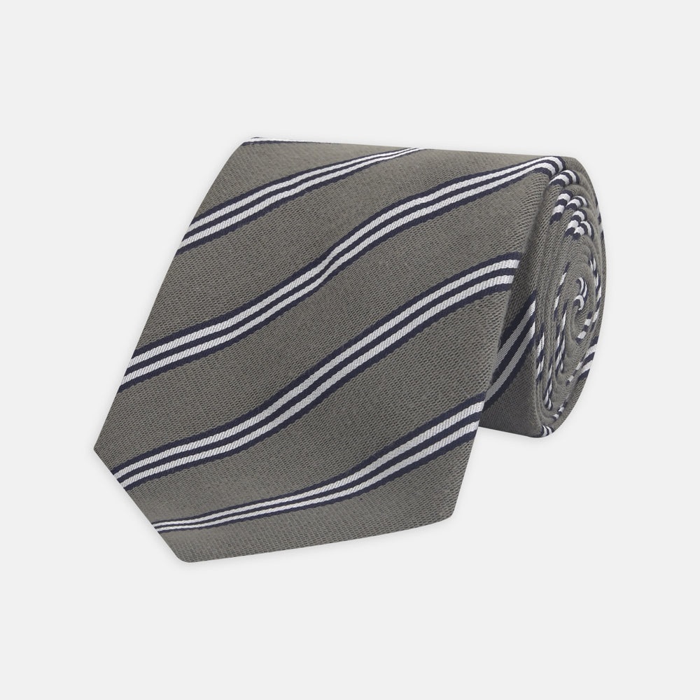 The Turnbull & Asser Grey Diagonal Stripe Cotton and Silk Tie features a navy, grey, and white striped pattern and is shown rolled up against a plain white background.
