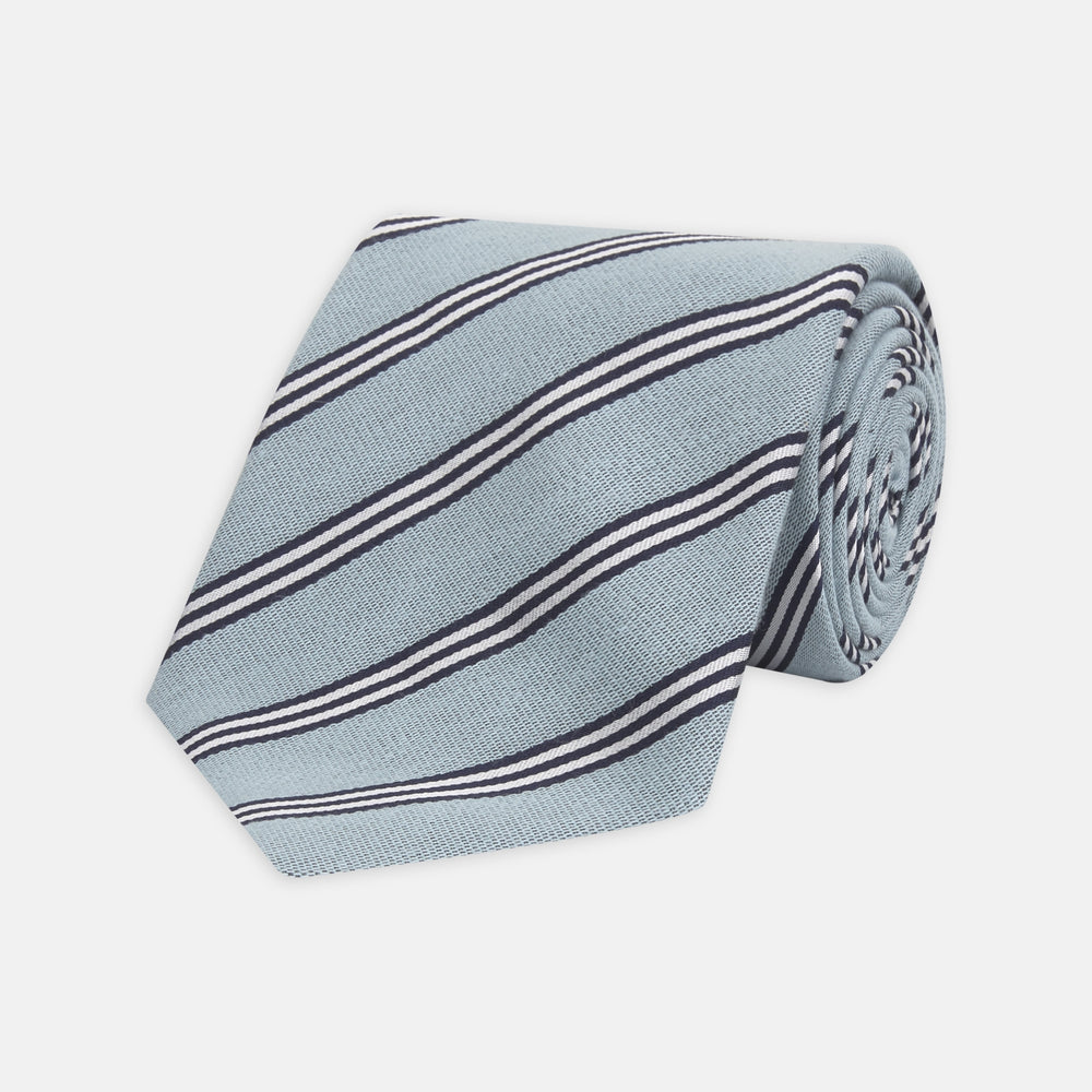 The Turnbull & Asser Powder Blue Diagonal Stripe Cotton and Silk Tie, featuring navy and white club stripes, is shown rolled up on a plain white background.