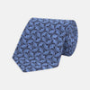 View 1 of product The Turnbull & Asser Blue Geo Silk Tie features a refined blue silk with a light blue abstract leaf pattern in a geometric design, rolled at one end and shown on a plain white background.
