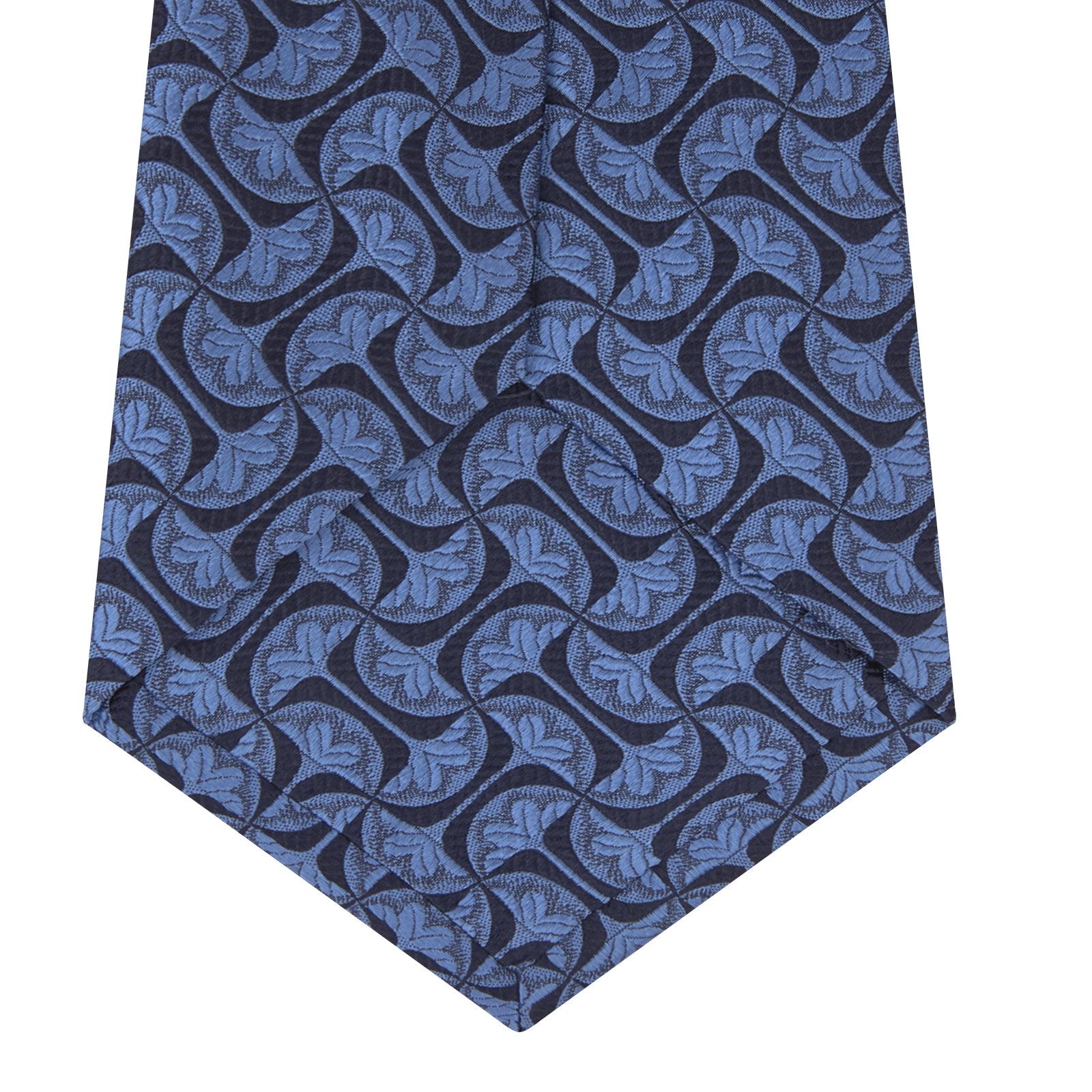 View 4 of product The Turnbull & Asser Blue Geo Silk Tie features a refined blue silk with a light blue abstract leaf pattern in a geometric design, rolled at one end and shown on a plain white background.