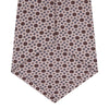 View 4 of product The Turnbull & Asser Pastel Pink Geometric Silk Tie features a small, repeating dark brown and white pattern for a mid-century look—ideal with tailored jackets. Shown rolled up on a white background.