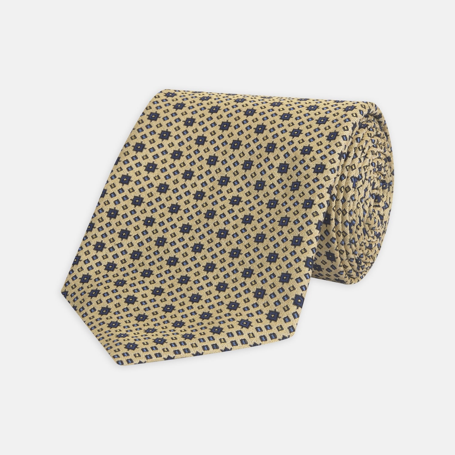 View 1 of product The Turnbull & Asser Pale Yellow Geometric Silk Tie features a subtle navy blue floral pattern and is displayed rolled on a white background.