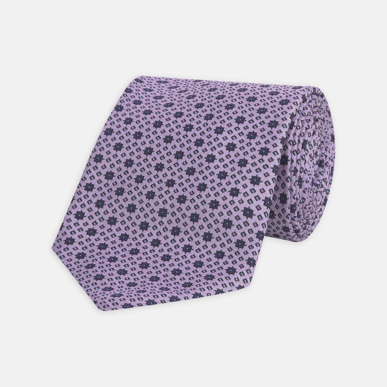 View 1 of product The Turnbull & Asser Lilac Geometric Silk Tie features a small, repeating mid-century motif in dark purple and black on white—an ideal accent for tailored jackets.