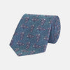 View 1 of product The Turnbull & Asser Turquoise Carp Silk Tie is woven in England, featuring a repeating white and brown carp design on a light blue background with intricate swirling patterns.