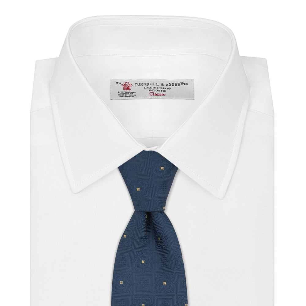 The Deep Turquoise Flower Mosaic Silk Tie by Turnbull & Asser features a jacquard design in blue with a subtle geometric pattern and small gold square accents evenly spaced across the fabric.