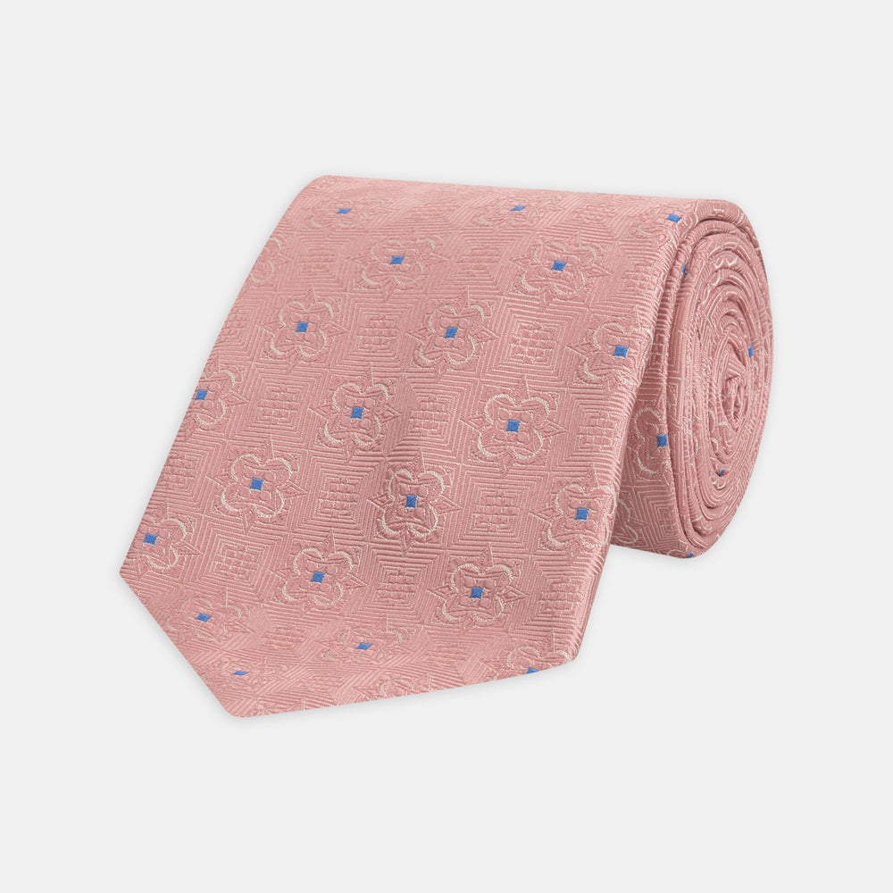 The Pink Flower Mosaic Silk Tie by Turnbull & Asser features a subtle jacquard texture with small blue floral accents, shown on a white background.
