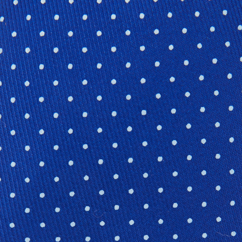 The Turnbull & Asser Royal Blue and White Small Spot Printed Silk Tie, shown rolled on a white background, features a refined spot pattern—ideal for complementing your office shirt.
