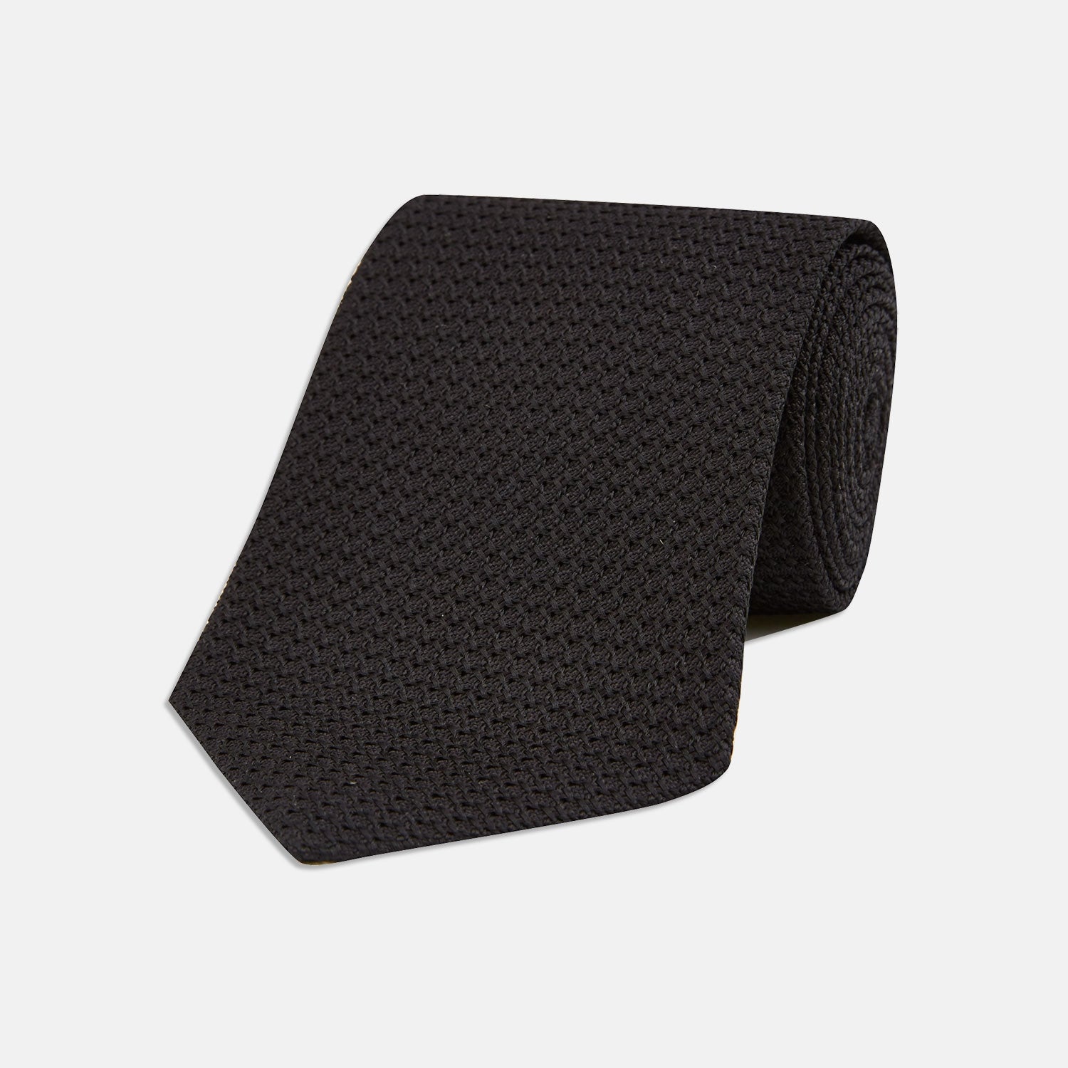 View 1 of product The Slim Black Grenadine Silk Tie by Turnbull & Asser, featuring a unique textured weave, is rolled up and displayed against a plain white background.