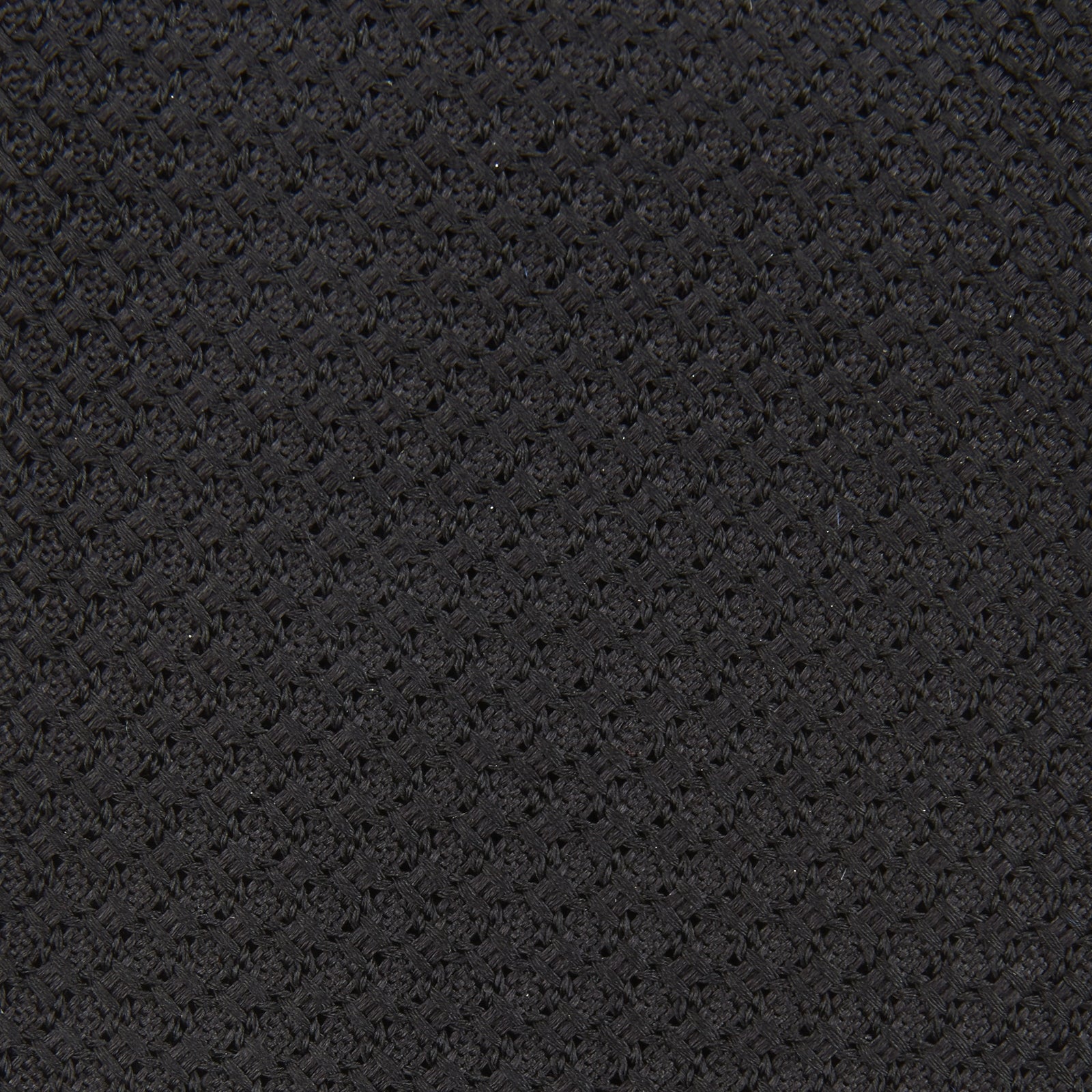 View 3 of product The Slim Black Grenadine Silk Tie by Turnbull & Asser, featuring a unique textured weave, is rolled up and displayed against a plain white background.
