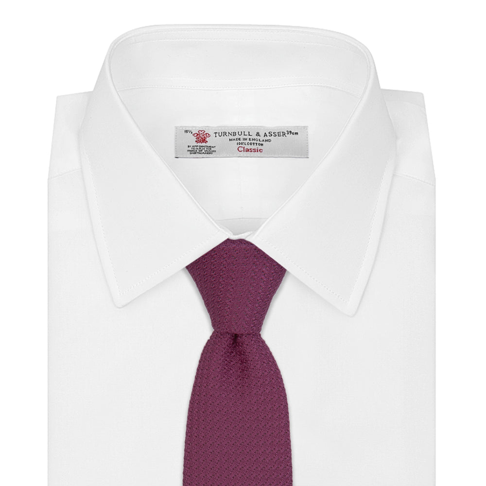 The Turnbull & Asser Wine Grenadine Silk Tie, featuring a textured weave in dark purple, is displayed rolled-up on a plain white background.