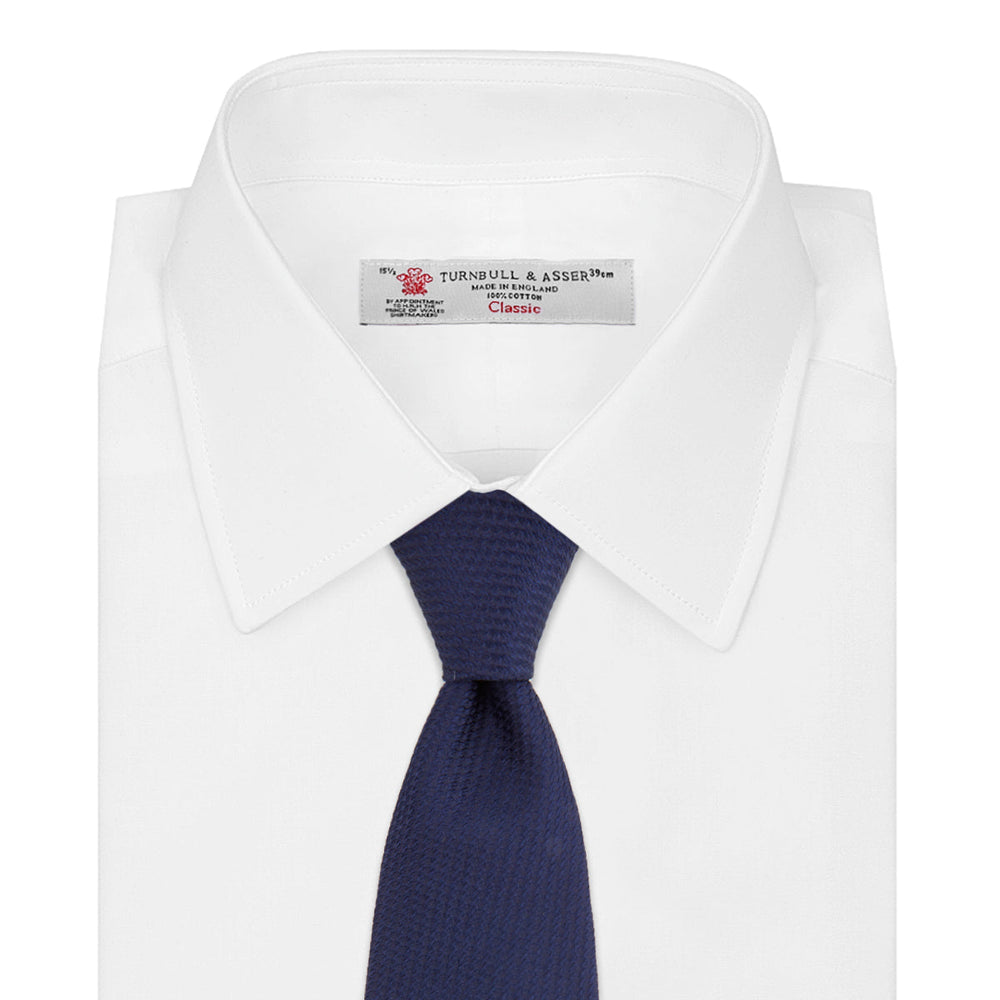 The Turnbull & Asser Navy Lace Silk Tie, featuring a subtle lace weave texture, is displayed rolled up on a plain white background.