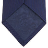 View 4 of product The Turnbull & Asser Navy Lace Silk Tie, featuring a subtle lace weave texture, is displayed rolled up on a plain white background.