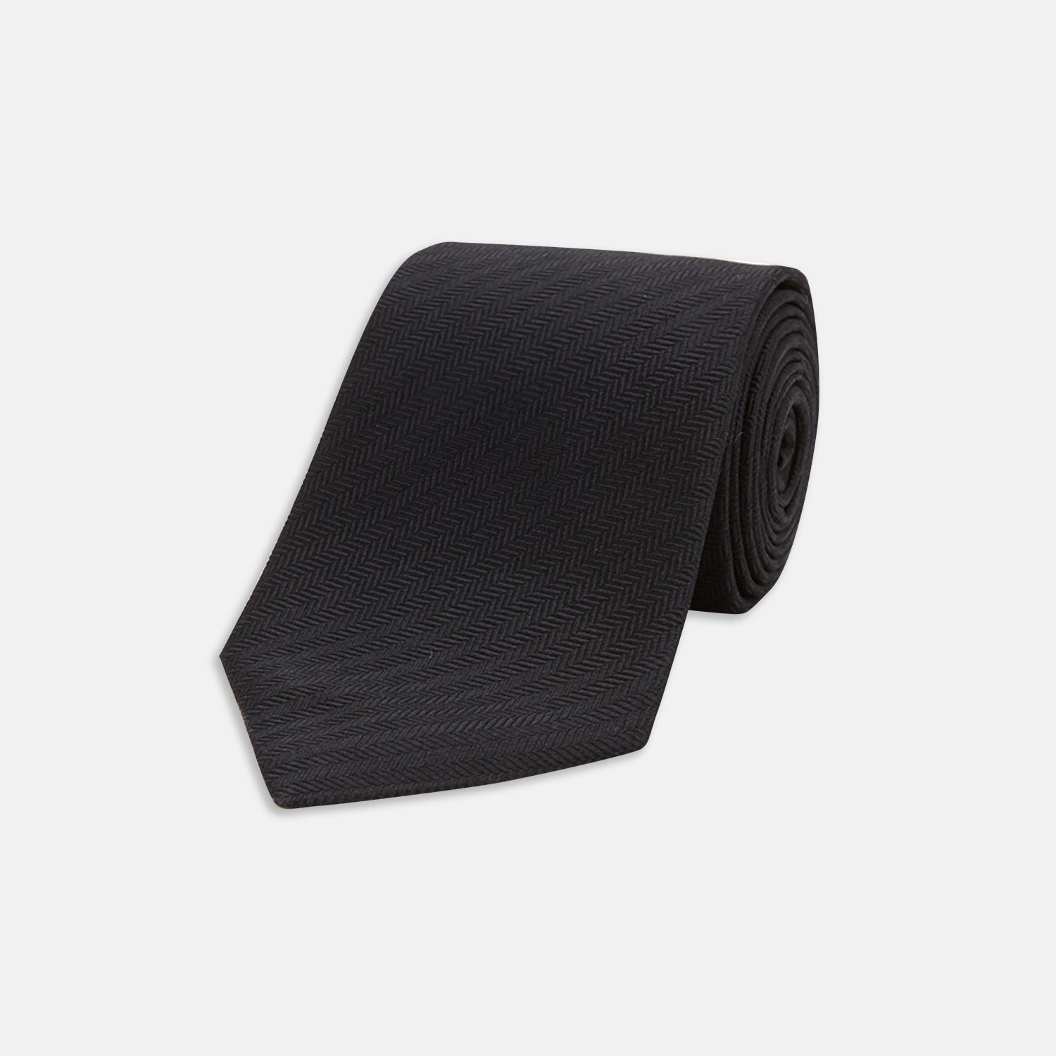 View 1 of product The Turnbull & Asser Seven-Fold Black Herringbone Silk Tie, featuring a subtle weave, is shown rolled up against a plain white background.
