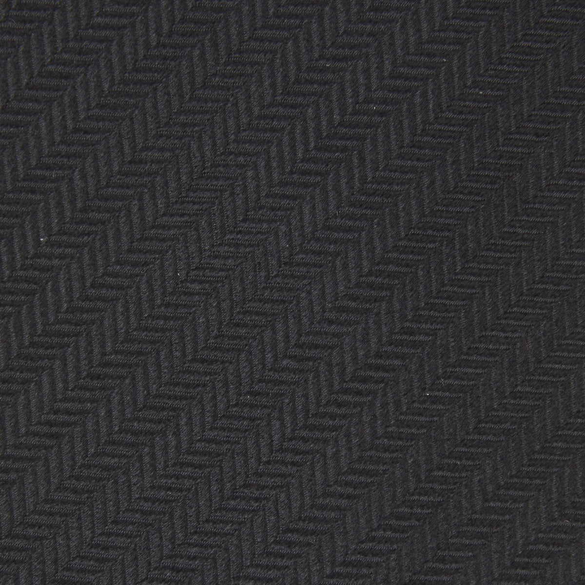 View 3 of product A Long Black Herringbone Silk Tie by Turnbull & Asser is shown rolled up on a plain white background.