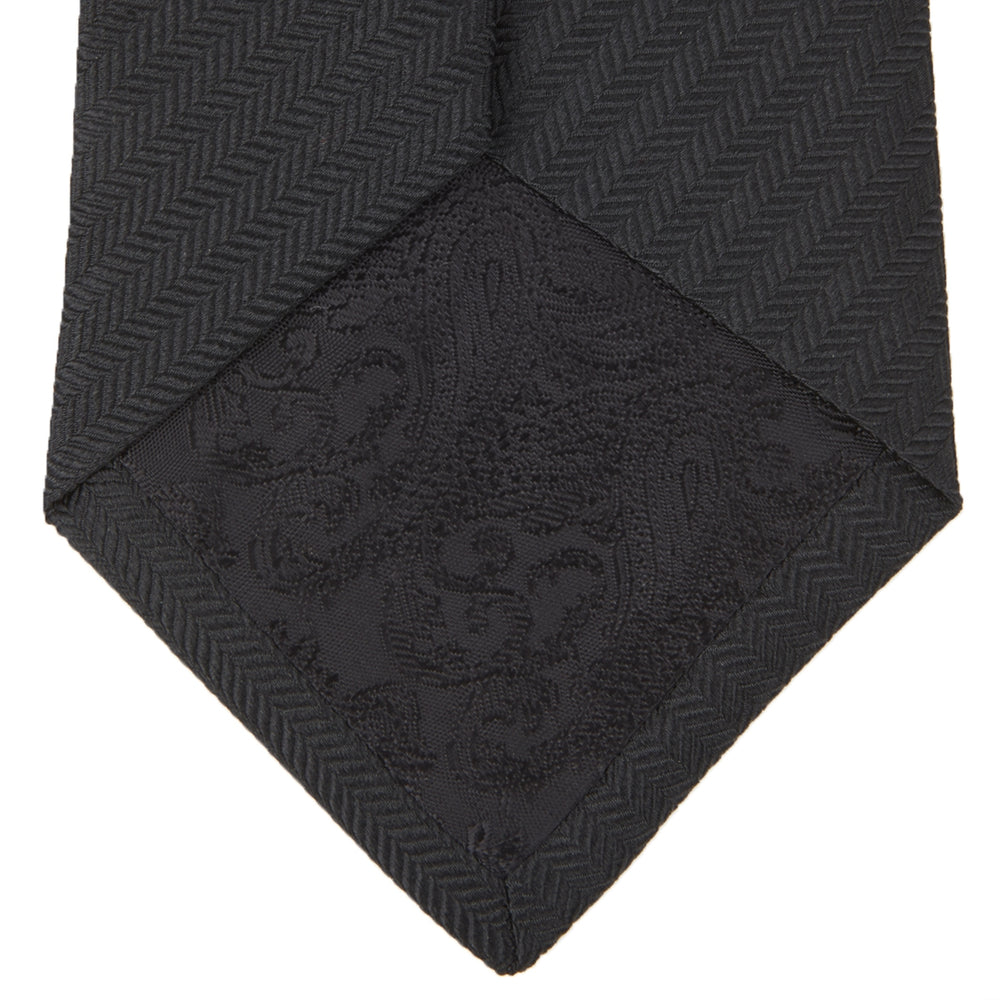 A Long Black Herringbone Silk Tie by Turnbull & Asser is shown rolled up on a plain white background.