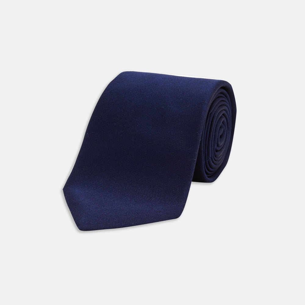 The Turnbull & Asser Long Navy Plain Satin Silk Tie is neatly rolled and displayed against a plain white background.