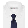 View 2 of product The Turnbull & Asser Seven-Fold Navy Plain Satin Silk Tie is neatly rolled and showcased against a plain light gray background.