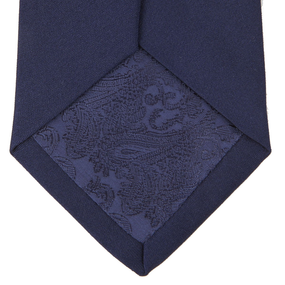 View 4 of product The Turnbull & Asser Seven-Fold Navy Plain Satin Silk Tie is neatly rolled and showcased against a plain light gray background.