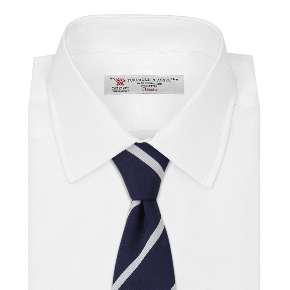 The Turnbull & Asser Long Navy and White Blazer Stripe Repp Silk Tie is shown rolled at one end, highlighting its diagonal stripes, against a plain white background.