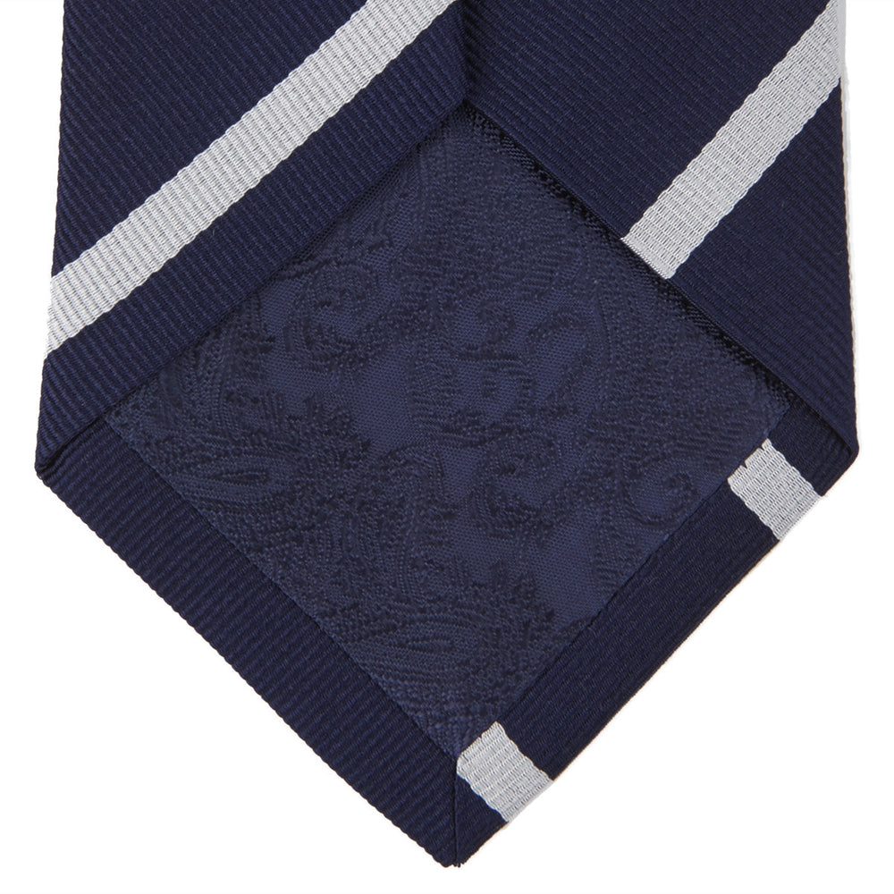 The Turnbull & Asser Long Navy and White Blazer Stripe Repp Silk Tie is shown rolled at one end, highlighting its diagonal stripes, against a plain white background.