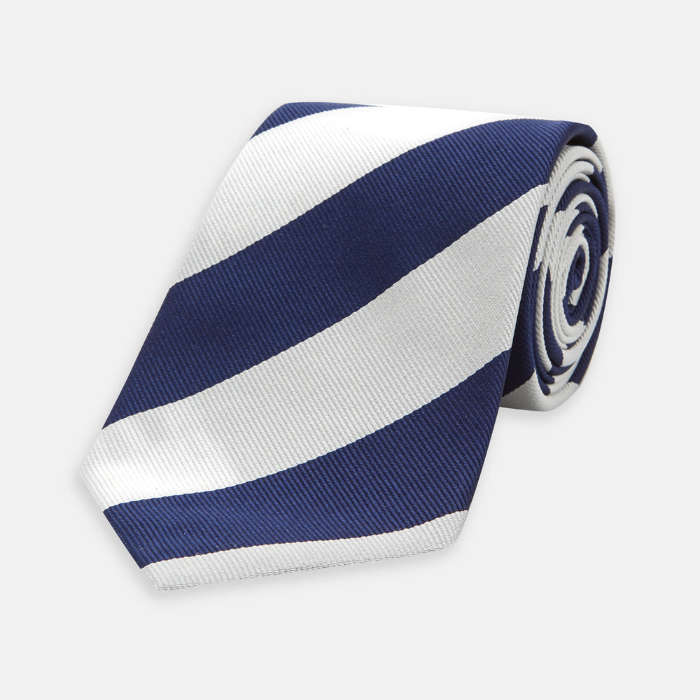 The Long Navy and Off-White Block Stripe Repp Silk Tie by Turnbull & Asser, featuring diagonal stripes, is rolled up and displayed on a plain white background—ideal for pairing with an office shirt.