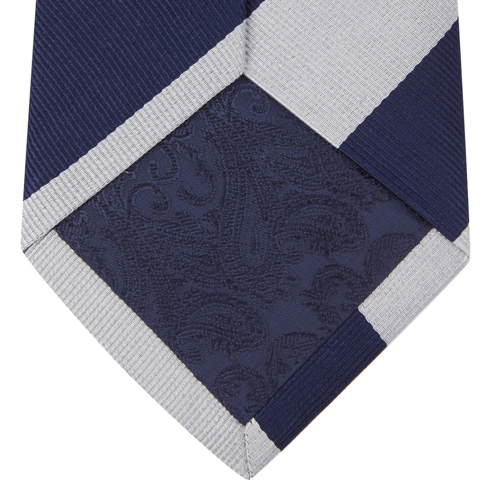 The Long Navy and Off-White Block Stripe Repp Silk Tie by Turnbull & Asser, featuring diagonal stripes, is rolled up and displayed on a plain white background—ideal for pairing with an office shirt.