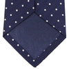 View 3 of product The Turnbull & Asser Seven-Fold Navy & White Spot Herringbone Silk Tie features a navy base with white polka dots and a classic herringbone weave, displayed rolled up on a plain white background.