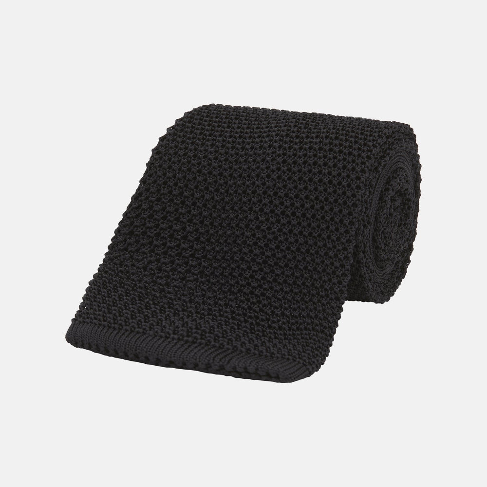 The Turnbull & Asser Black Knitted Silk Tie features a textured pattern and is displayed rolled up on a white background—a stylish, versatile accessory perfect for elevating any gentleman's wardrobe.