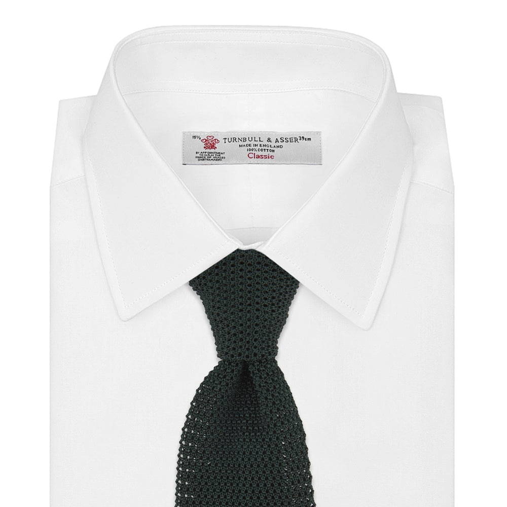 The Turnbull & Asser Green Knitted Silk Tie features a rich dark green hue and textured weave, making it an elegant accessory for any gentleman's wardrobe, shown rolled up against a light background.