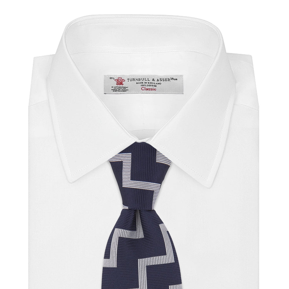 The Navy and White Striped Zigzag Silk Tie by Turnbull & Asser, shown rolled on a white background, features bold zigzag stripes—an ideal accessory for the modern gentleman’s everyday style.