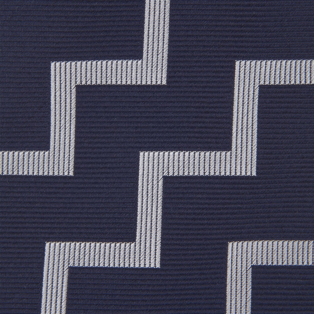 The Navy and White Striped Zigzag Silk Tie by Turnbull & Asser, shown rolled on a white background, features bold zigzag stripes—an ideal accessory for the modern gentleman’s everyday style.