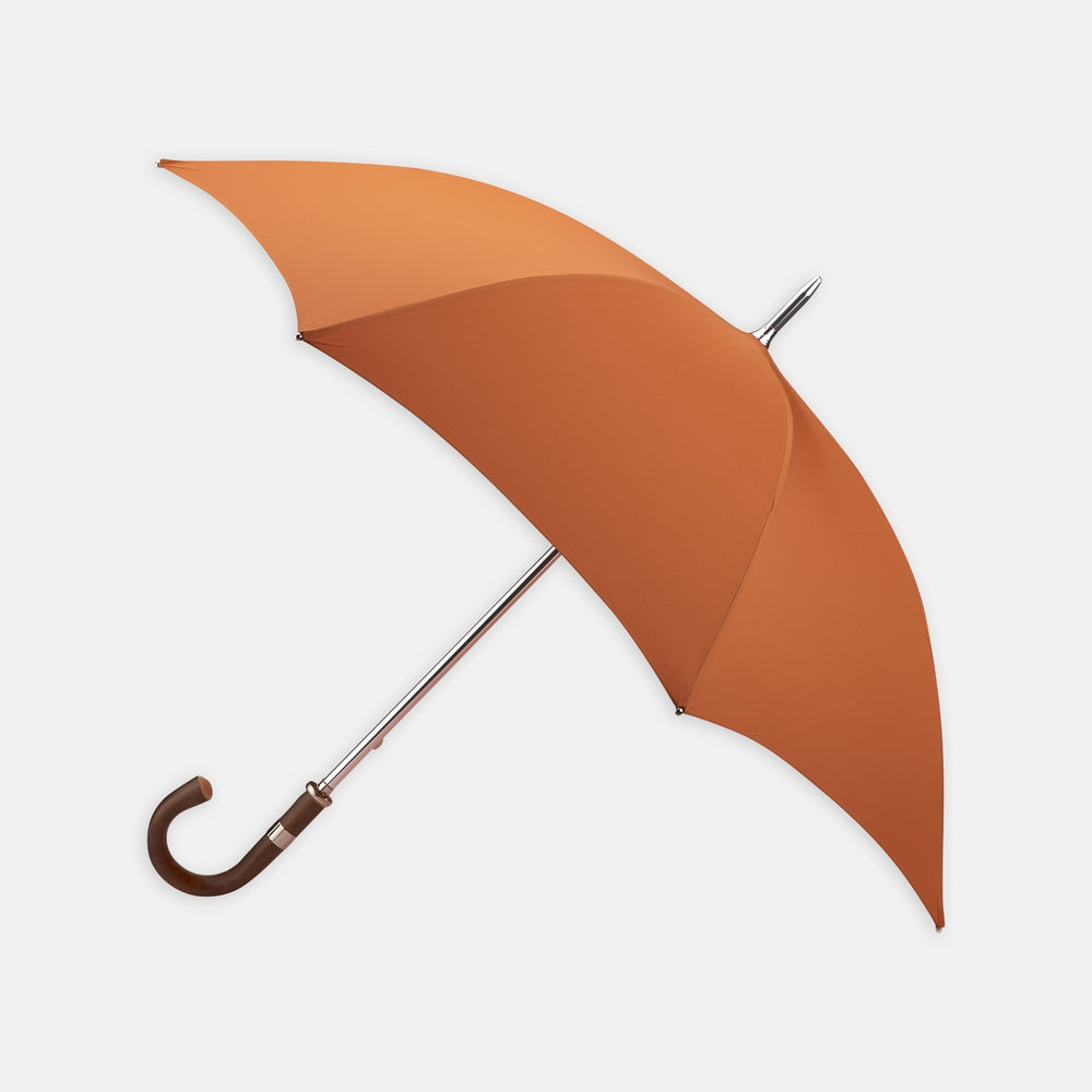 The Turnbull & Asser Orange Umbrella with Chestnut Crook features a vibrant canopy, elegant curved chestnut handle, and sturdy metal shaft, offering stylish weather protection. Displayed on a white background.