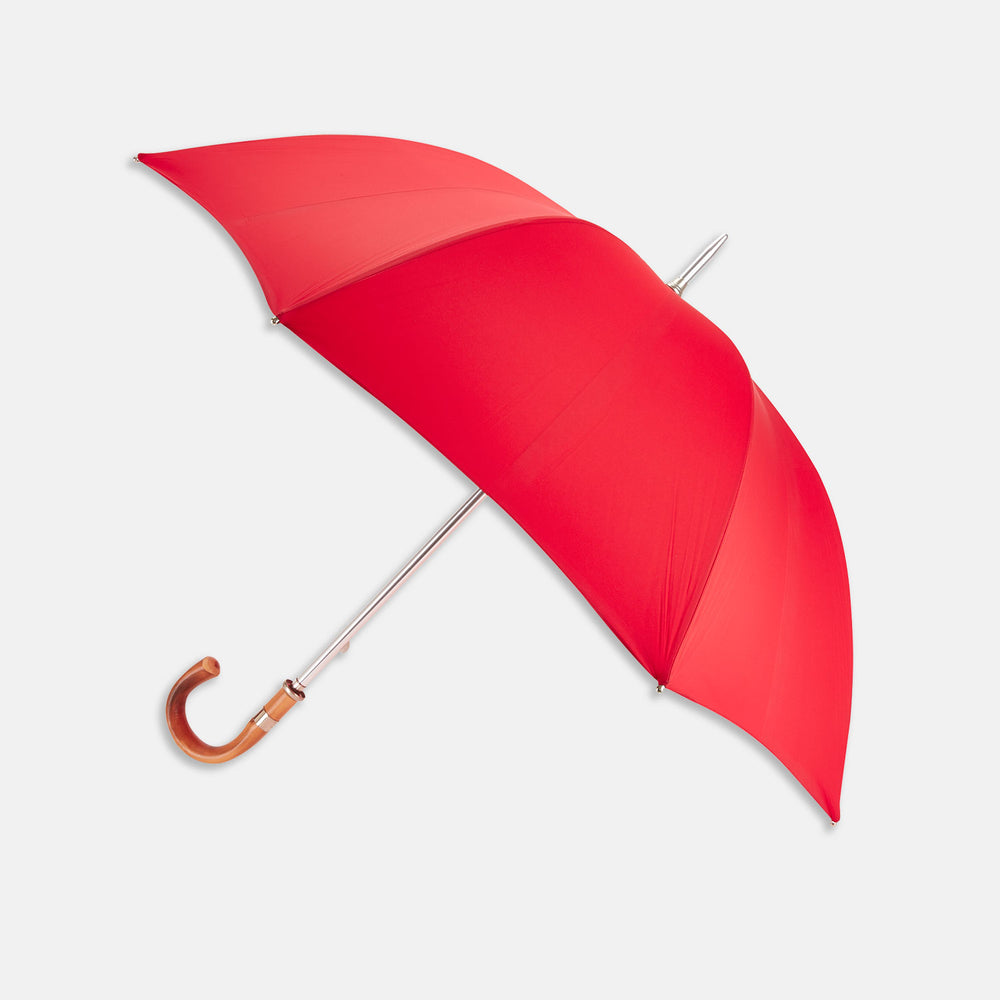 The Turnbull & Asser Red Umbrella with Chestnut Crook features a stylish wooden handle and sturdy metal shaft—an elegant, practical accessory ideal for facing unpredictable English weather.