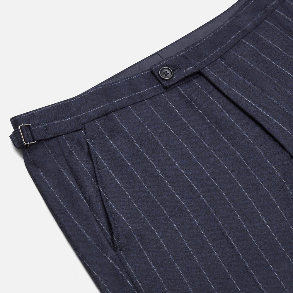 The Navy Pinstripe Henry Trousers by Turnbull & Asser feature vertical white stripes, a tailored fit, button closure, and belt loops. Crafted from a wool cashmere blend, they are shown against a plain white background.