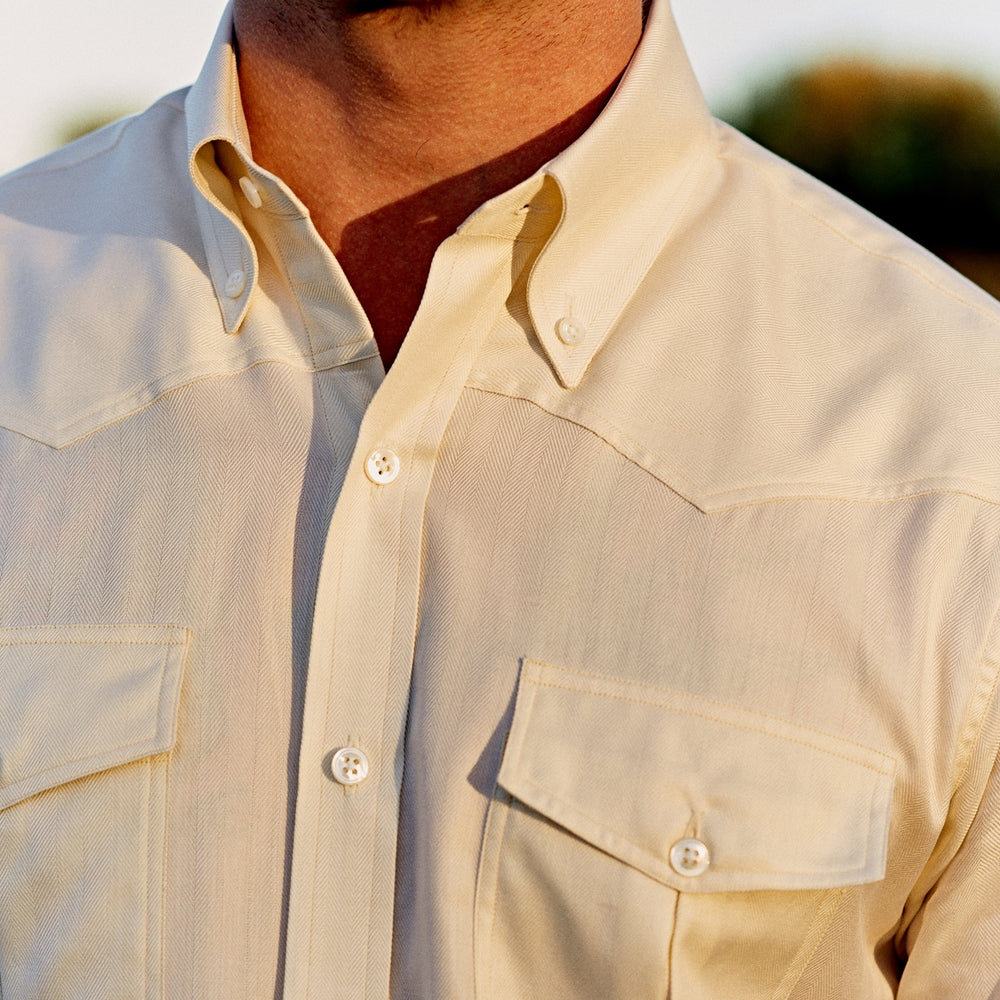 The Turnbull & Asser Weekend Fit Cream Herringbone Western Shirt features a Norfolk collar, button cuffs, and chest pockets, elegantly folded and displayed on a plain white background.