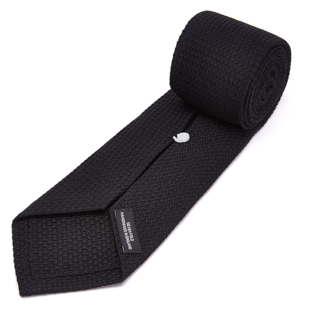 The Turnbull & Asser Seven-Fold Black Grenadine Silk Tie, displayed on a white background, adds a refined touch of luxury neckwear.
