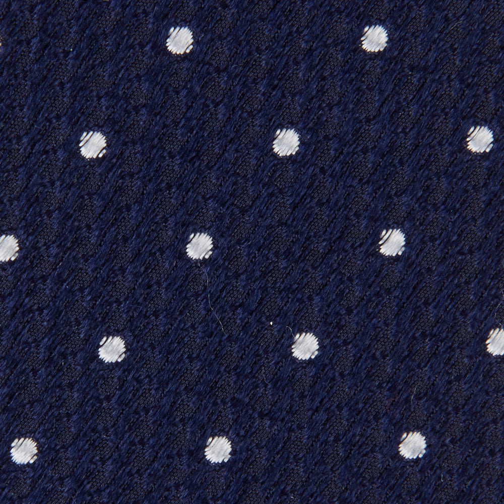 The Seven-Fold Navy and White Spot Lace Silk Tie by Turnbull & Asser showcases a luxurious navy silk with white spots, elegantly rolled and presented on a white background.