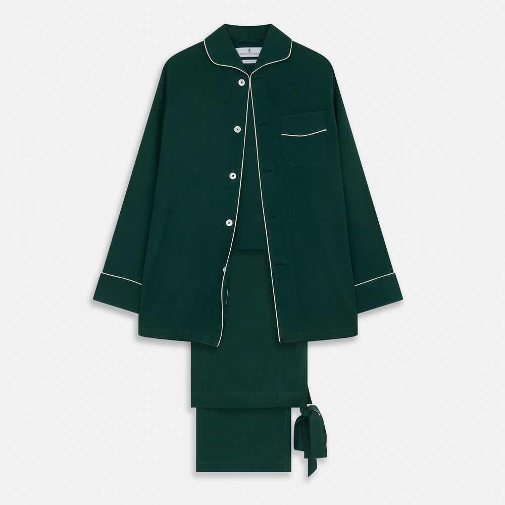 The Turnbull & Asser Dark Green Silk Pyjama Set features a long-sleeve button-up top with white piping, chest pocket, and matching pants, all neatly folded on a plain white background.