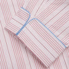 View 3 of product The Turnbull & Asser Pink And White Stripe Twill Cotton Pyjama Set features long sleeves and pants with a curved collar and blue trim on the cuffs, pocket, and hem—a classic gent’s style shown on a plain white background.
