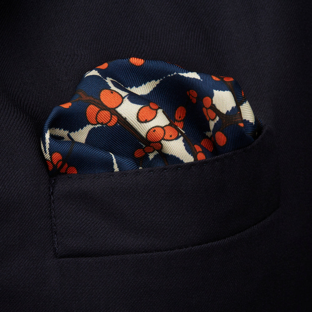 The Blue Berry Floral Pocket Square by Turnbull & Asser features a navy blue silk background with red berry and white leaf designs, plus small labels on two corners—making it a perfect festive gift.