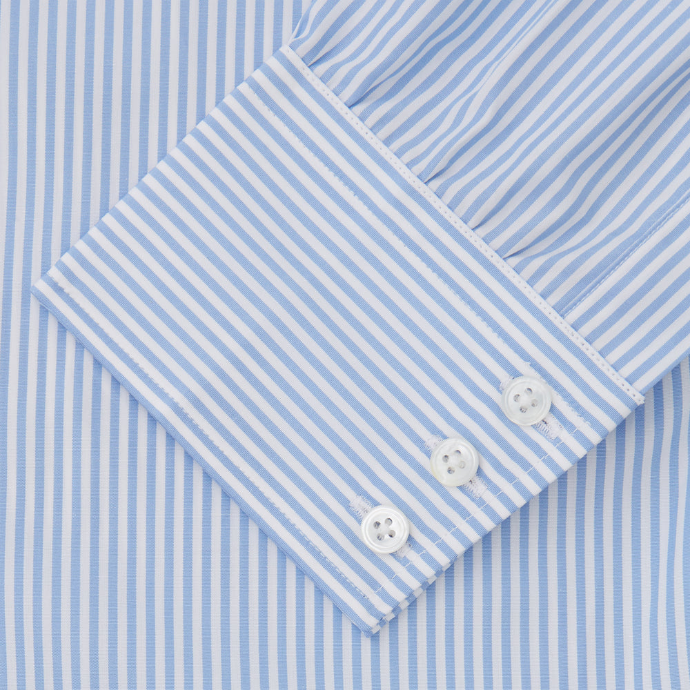 The Turnbull & Asser Light Blue Bengal Stripe Shirt features white vertical stripes, a classic T&A collar, and 3-button cuffs. Buttoned down the front, it’s laid flat on a white background for a timeless British look.