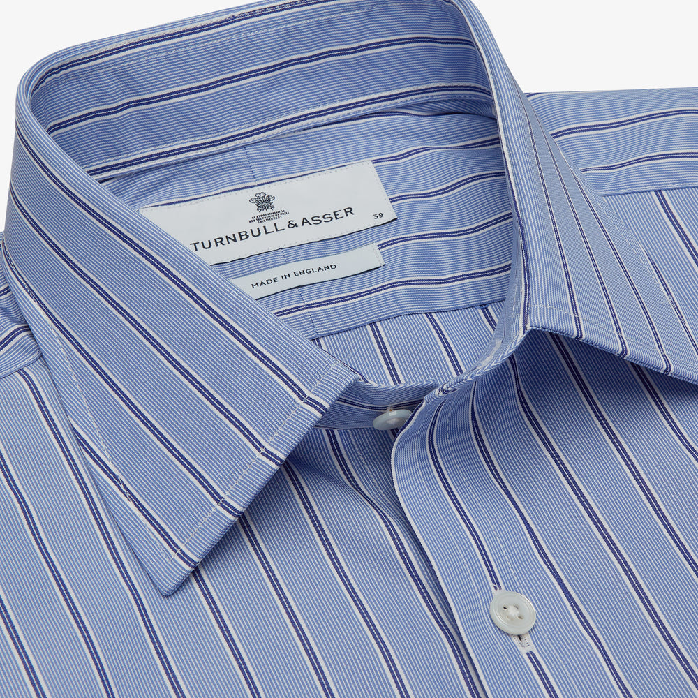 A neatly folded Turnbull & Asser Blue Stripe Regular Fit Shirt with T&A collar and square double cuffs, featuring long sleeves and thin white stripes on a light blue base, displayed on a plain white background.