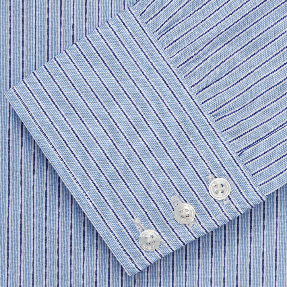 Turnbull & Asser’s Blue Stripe Shirt features thin vertical white stripes, a T&A collar, 3-button cuffs, white buttons, and a regular fit. Smart-casual style displayed flat on a white background.