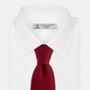 View 2 of product The Turnbull & Asser Burgundy Abstract Tonal Silk Jacquard Tie is shown rolled up with a subtle textured pattern on a plain white background—an elegant formalwear choice.