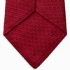 View 4 of product The Turnbull & Asser Burgundy Abstract Tonal Silk Jacquard Tie is shown rolled up with a subtle textured pattern on a plain white background—an elegant formalwear choice.